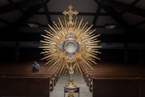 Man praying in front of Eucharistic Monstrance